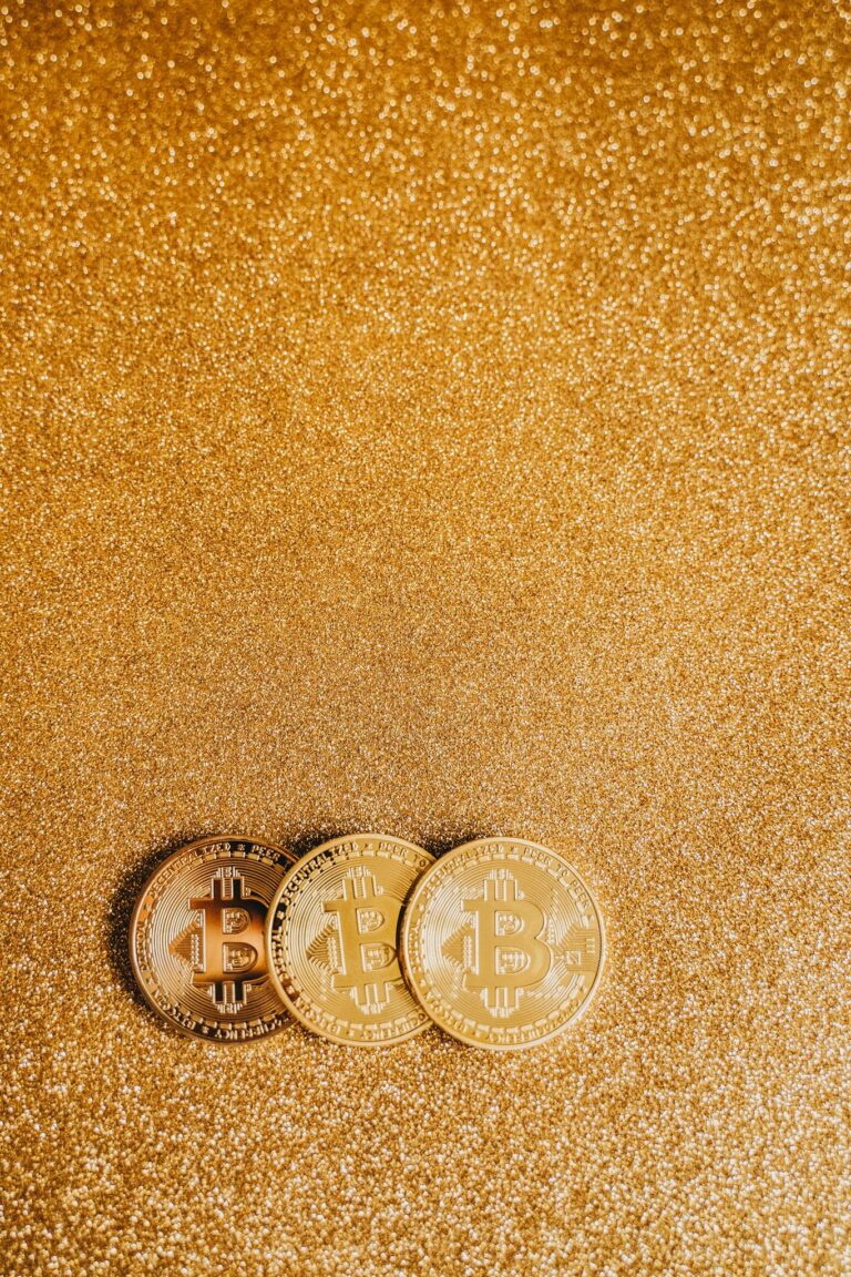 Three Bitcoin coins on a shimmering gold background, ideal for finance or cryptocurrency themes.